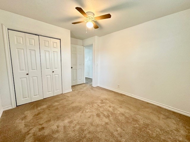 unfurnished bedroom featuring light colored carpet, ceiling fan, and a closet