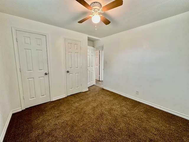 unfurnished bedroom with ceiling fan and dark carpet