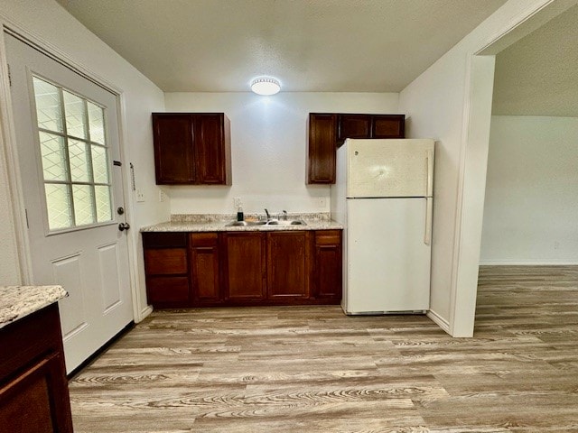 kitchen featuring light hardwood / wood-style floors, sink, white fridge, and light stone countertops