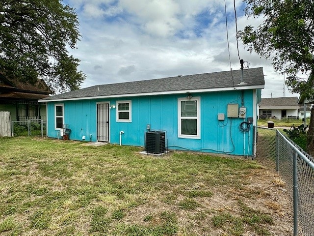 back of property with central AC and a yard