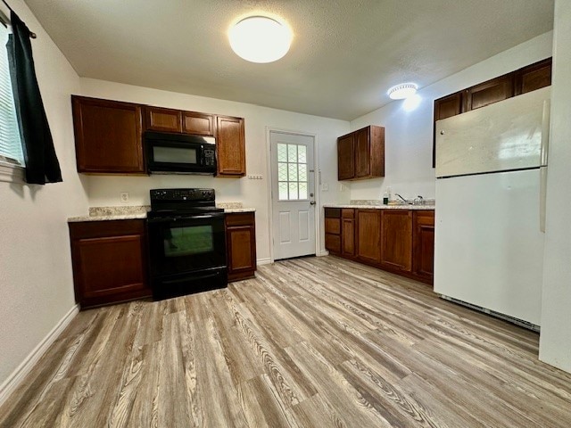 kitchen with light wood-type flooring, a textured ceiling, and black appliances