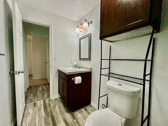 bathroom featuring vanity, wood-type flooring, a textured ceiling, and toilet