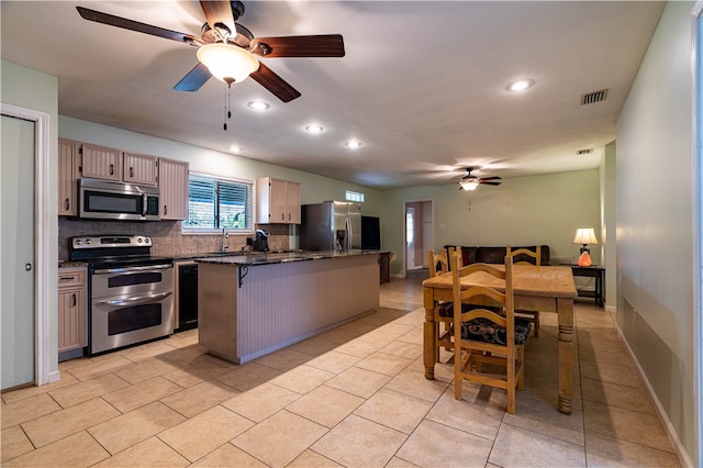 kitchen with a kitchen bar, appliances with stainless steel finishes, backsplash, light brown cabinets, and a center island