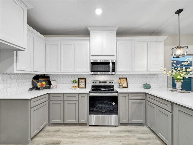 kitchen featuring pendant lighting, gray cabinets, tasteful backsplash, and appliances with stainless steel finishes