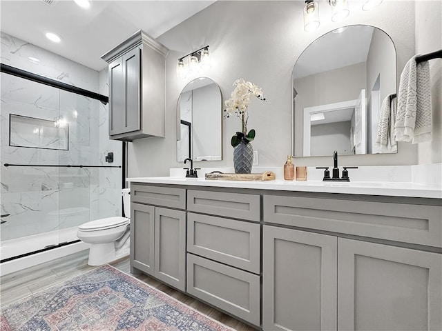 bathroom featuring a shower with door, vanity, hardwood / wood-style floors, and toilet