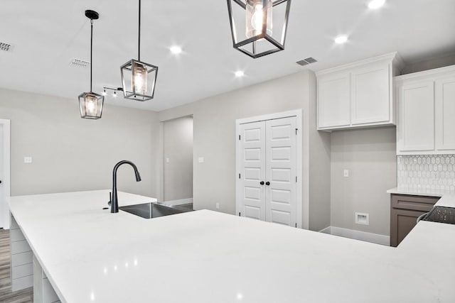 kitchen featuring hanging light fixtures, decorative backsplash, sink, and white cabinets