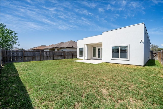 back of property with stucco siding, a fenced backyard, french doors, a yard, and a patio area