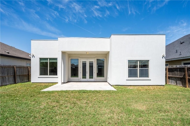 rear view of property featuring french doors, a lawn, a fenced backyard, and stucco siding