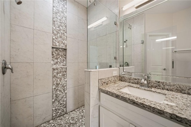 bathroom featuring tiled shower and vanity