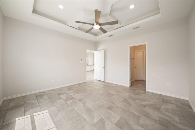 spare room with visible vents, a raised ceiling, baseboards, and a ceiling fan