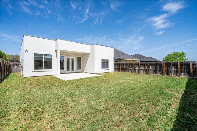 rear view of house featuring a yard, french doors, a fenced backyard, and stucco siding