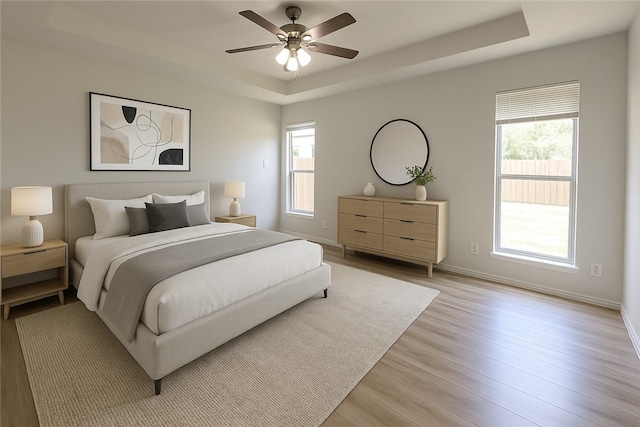 5411 Cypress Cir, Kingsville, TX 78363 - bedroom featuring ceiling fan, baseboards, light wood-type flooring, and a raised ceiling