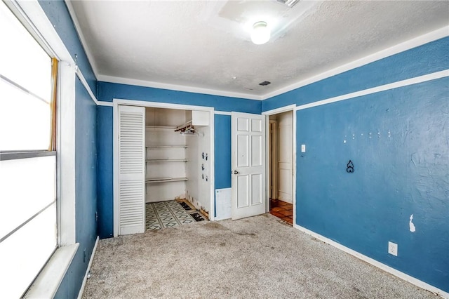 unfurnished bedroom with carpet floors, a textured ceiling, baseboards, and a closet