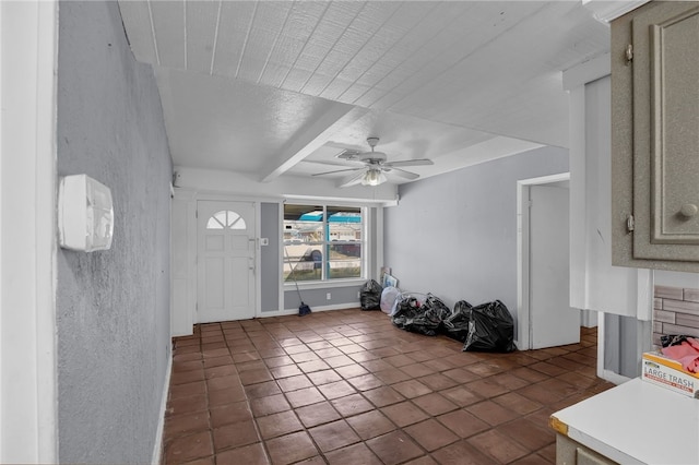 foyer with ceiling fan, baseboards, beam ceiling, and a textured wall