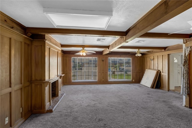 interior space with light carpet, a large fireplace, wooden walls, and beamed ceiling