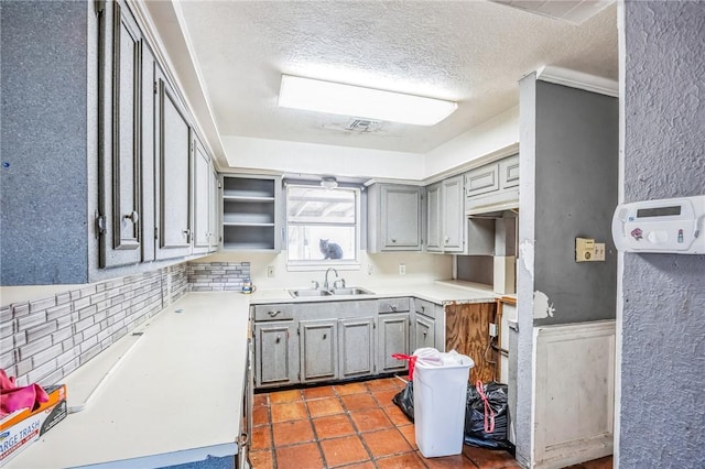 kitchen featuring decorative backsplash, gray cabinetry, a sink, a textured ceiling, and tile patterned flooring