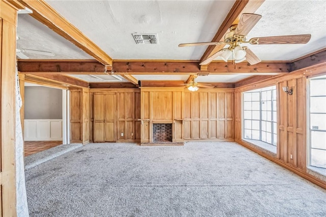 interior space with ceiling fan, a decorative wall, visible vents, beamed ceiling, and carpet