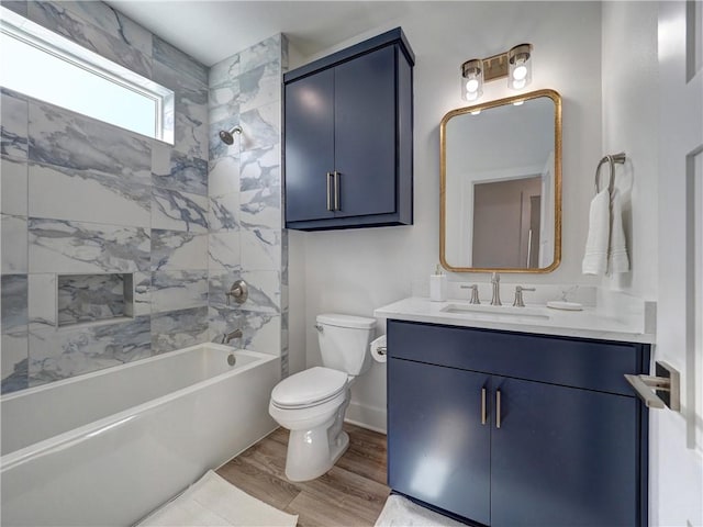 bathroom with toilet, vanity, wood finished floors,  shower combination, and baseboards