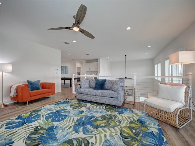 living area with a ceiling fan, recessed lighting, visible vents, and wood finished floors