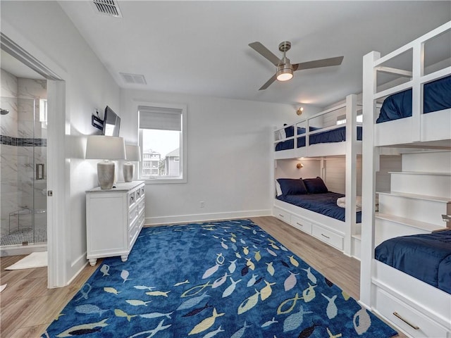 bedroom with ensuite bath, wood finished floors, visible vents, and baseboards