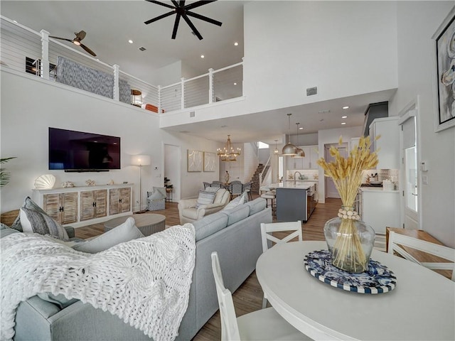 living room featuring dark wood-type flooring, recessed lighting, stairway, and ceiling fan with notable chandelier