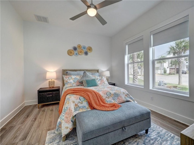 bedroom with a ceiling fan, baseboards, visible vents, and wood finished floors