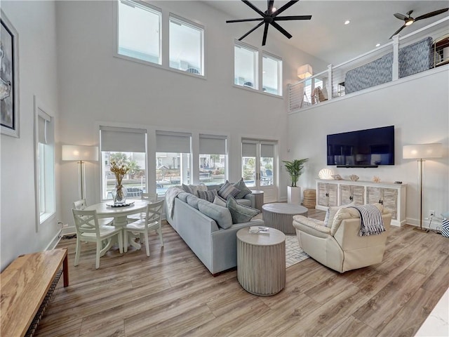 living area featuring light wood-style floors, baseboards, and a ceiling fan