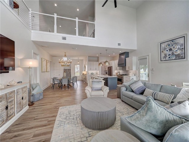 living area featuring light wood-style floors, baseboards, visible vents, and a notable chandelier