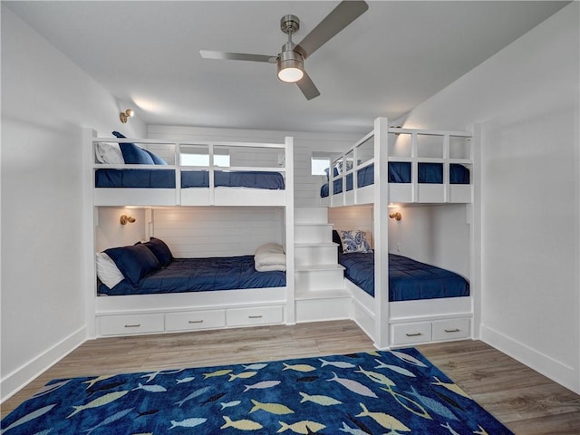 bedroom with ceiling fan, wood finished floors, and baseboards