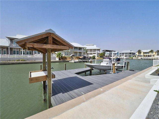 view of dock with a water view, boat lift, and a residential view