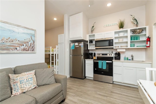 kitchen with appliances with stainless steel finishes, open floor plan, a sink, and open shelves