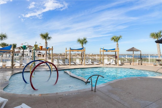 community pool with a patio area, fence, and playground community