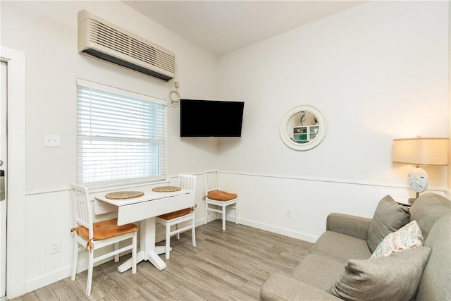 living area featuring an AC wall unit, baseboards, and wood finished floors