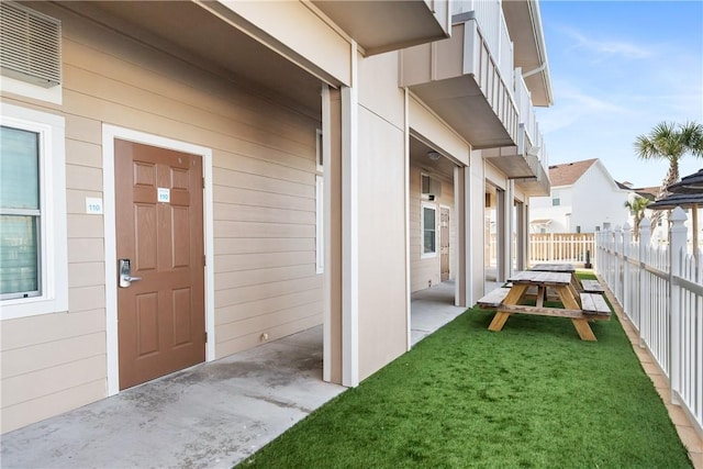 entrance to property with a patio area, fence, and a yard