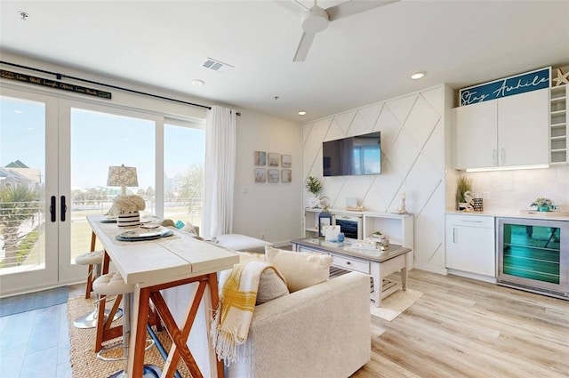 living room with a wealth of natural light, light hardwood / wood-style floors, and beverage cooler