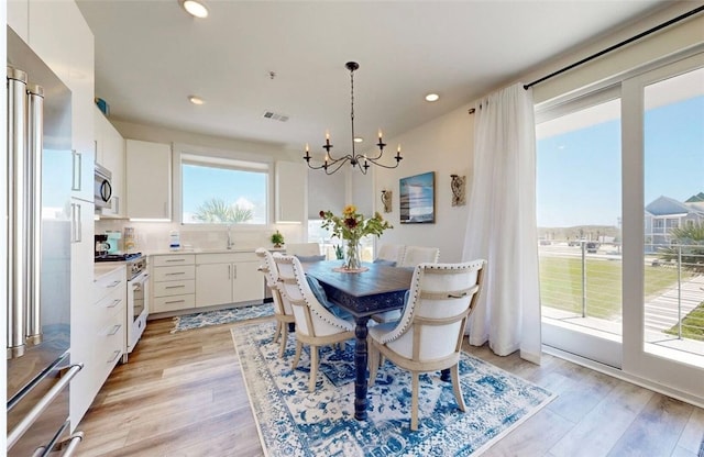 dining space with a chandelier, sink, and light hardwood / wood-style flooring