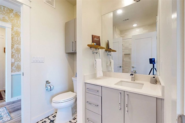 bathroom featuring tiled shower, wood-type flooring, toilet, and vanity