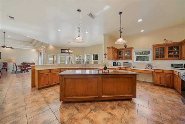 kitchen with hanging light fixtures, kitchen peninsula, ornamental molding, and a center island