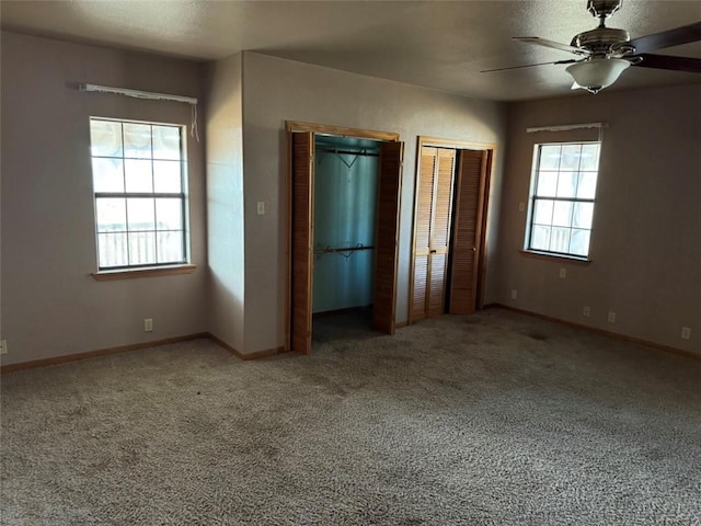 unfurnished bedroom with ceiling fan, carpet floors, and two closets