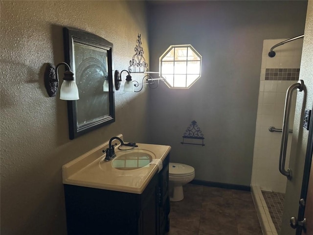 bathroom with tile patterned flooring, vanity, a tile shower, and toilet