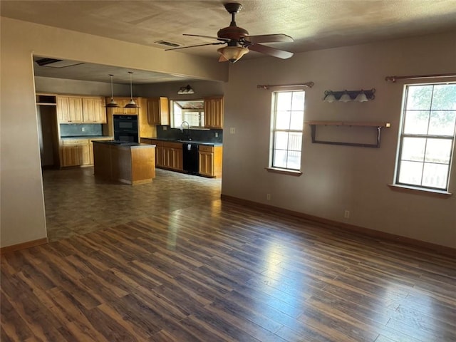 kitchen featuring pendant lighting, sink, dark hardwood / wood-style floors, a center island, and black appliances