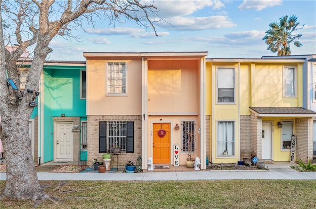 multi unit property with a front yard and brick siding