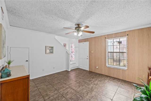 entrance foyer featuring a ceiling fan, wood walls, and a textured ceiling