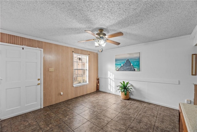 foyer featuring a textured ceiling, wood walls, a ceiling fan, and crown molding