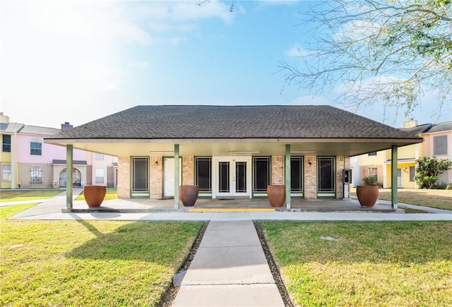 view of front of home with covered porch, roof with shingles, a front lawn, and brick siding