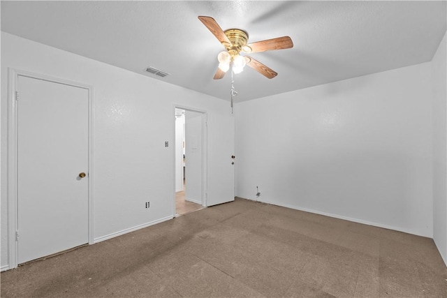 spare room with carpet floors, visible vents, and a ceiling fan