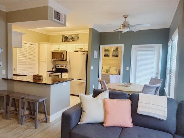 14802 Whitecap Blvd Unit 3-106, Corpus Christi, TX 78418 - kitchen featuring stainless steel appliances, dark countertops, light wood-type flooring, a ceiling fan, and a kitchen breakfast bar