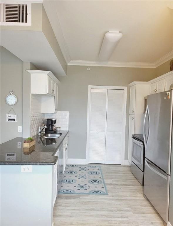 14802 Whitecap Blvd Unit 3-106, Corpus Christi, TX 78418 - kitchen featuring stainless steel appliances, white cabinets, crown molding, light wood-type flooring, and tasteful backsplash