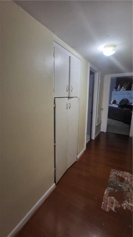 corridor with dark wood-style flooring and baseboards