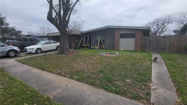 view of front facade with a playground, fence, a garage, driveway, and a front lawn